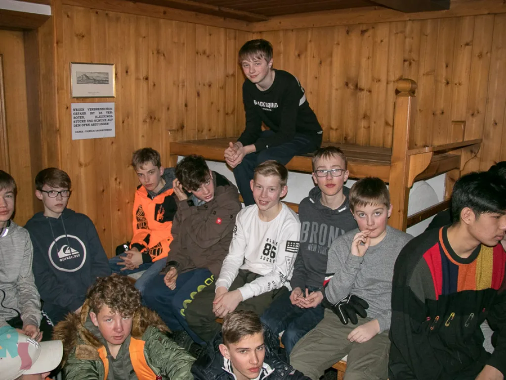 Jugendliche sitzen abends in der holzvertäfelten Stube.
